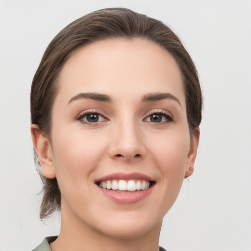 Joyful white young-adult female with medium  brown hair and grey eyes