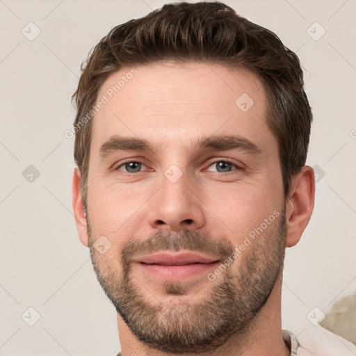 Joyful white young-adult male with short  brown hair and grey eyes