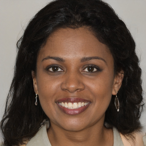 Joyful black young-adult female with long  brown hair and brown eyes