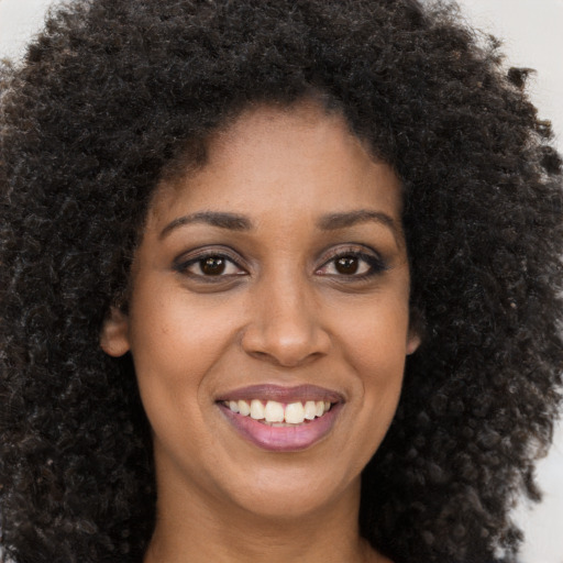 Joyful black young-adult female with long  brown hair and brown eyes