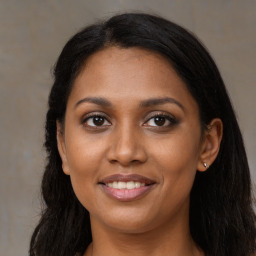 Joyful black young-adult female with long  brown hair and brown eyes