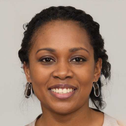 Joyful black young-adult female with long  black hair and brown eyes