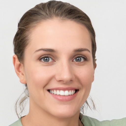 Joyful white young-adult female with medium  brown hair and grey eyes