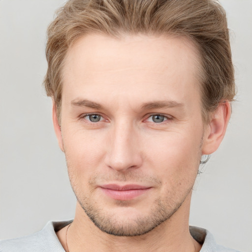 Joyful white young-adult male with short  brown hair and grey eyes