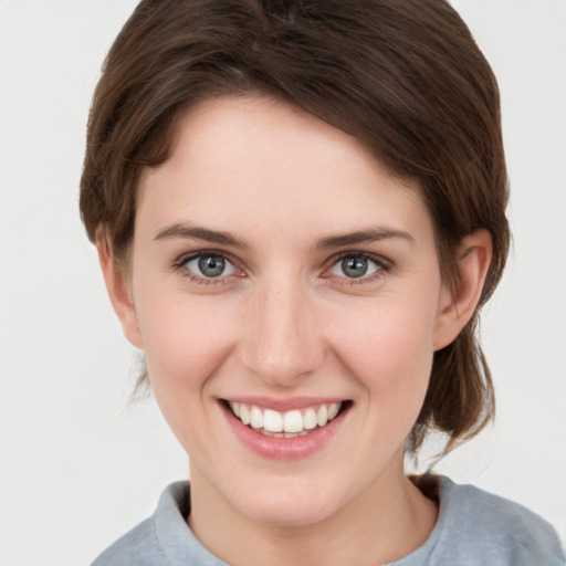 Joyful white young-adult female with medium  brown hair and grey eyes