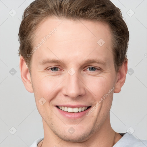 Joyful white young-adult male with short  brown hair and grey eyes