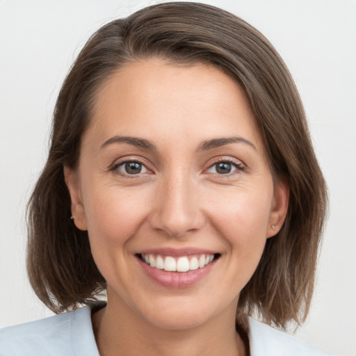 Joyful white young-adult female with medium  brown hair and grey eyes