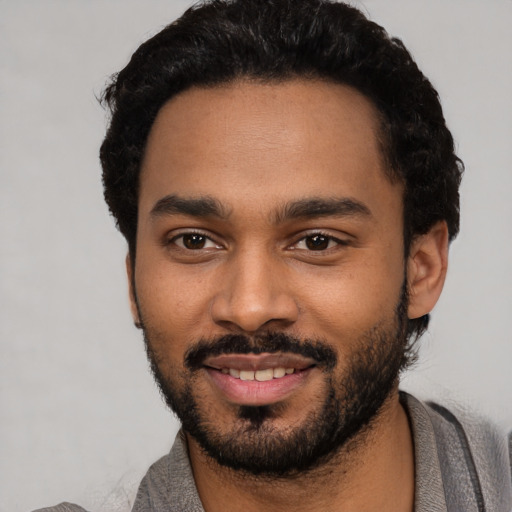 Joyful black young-adult male with short  black hair and brown eyes