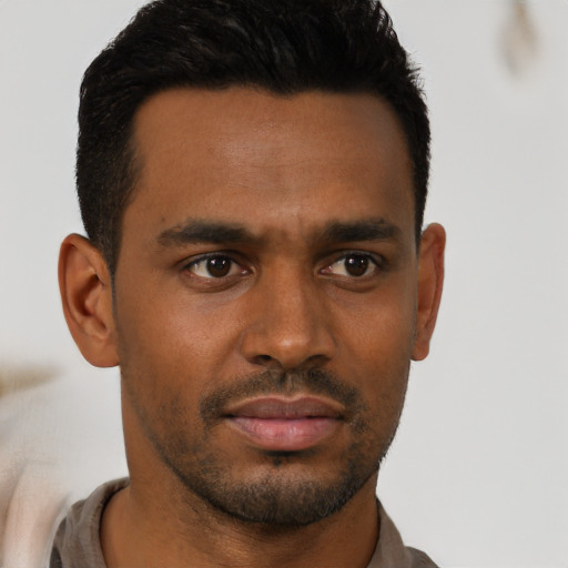 Joyful black young-adult male with short  brown hair and brown eyes