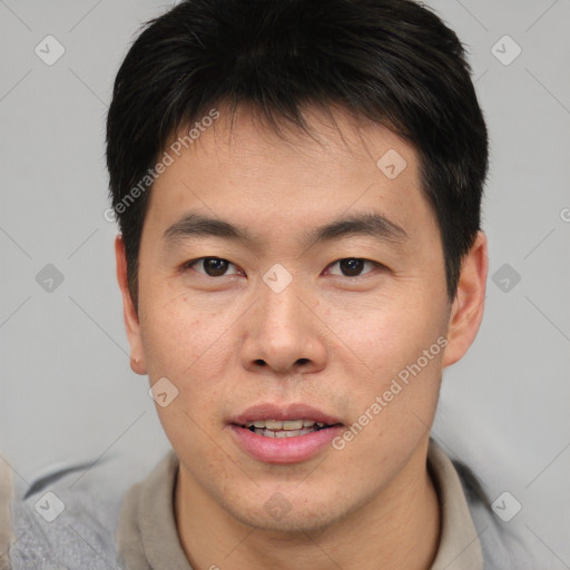 Joyful asian young-adult male with short  brown hair and brown eyes