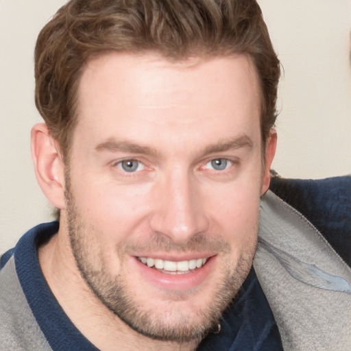 Joyful white young-adult male with short  brown hair and blue eyes