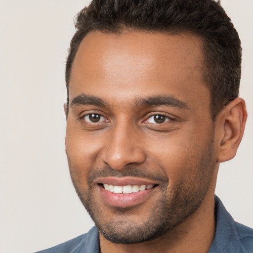 Joyful black young-adult male with short  brown hair and brown eyes