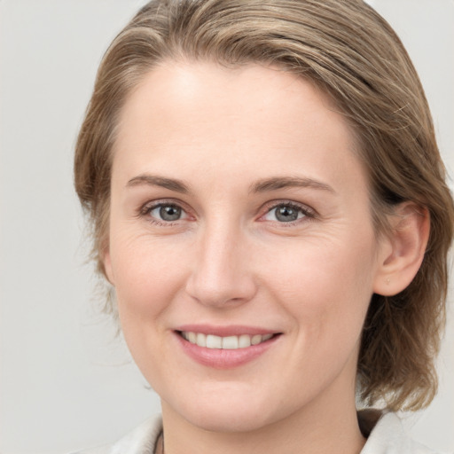 Joyful white young-adult female with medium  brown hair and grey eyes