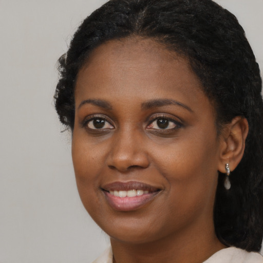 Joyful black young-adult female with long  brown hair and brown eyes