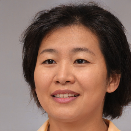Joyful asian adult female with medium  brown hair and brown eyes
