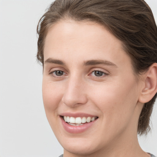 Joyful white young-adult female with medium  brown hair and grey eyes