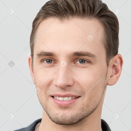 Joyful white young-adult male with short  brown hair and grey eyes