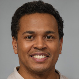 Joyful black young-adult male with short  brown hair and brown eyes