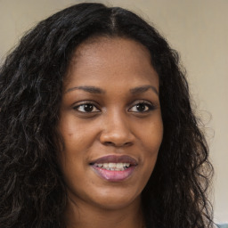 Joyful black young-adult female with long  brown hair and brown eyes