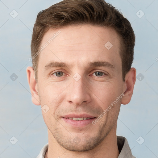 Joyful white young-adult male with short  brown hair and grey eyes