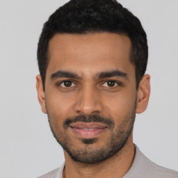 Joyful latino young-adult male with short  black hair and brown eyes