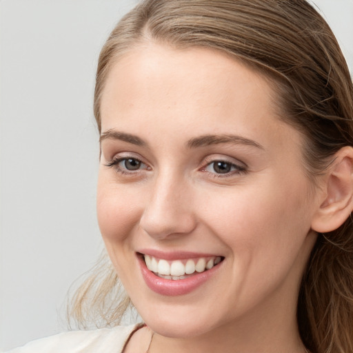 Joyful white young-adult female with long  brown hair and blue eyes