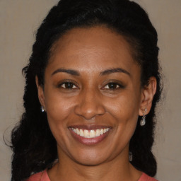 Joyful black young-adult female with long  brown hair and brown eyes