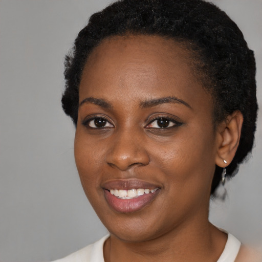 Joyful black young-adult female with short  black hair and brown eyes