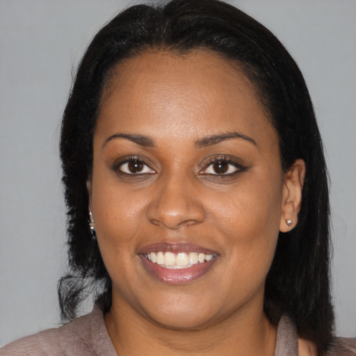Joyful black young-adult female with long  brown hair and brown eyes