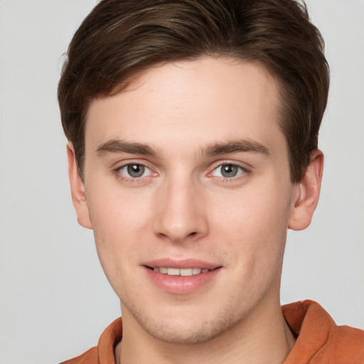 Joyful white young-adult male with short  brown hair and grey eyes