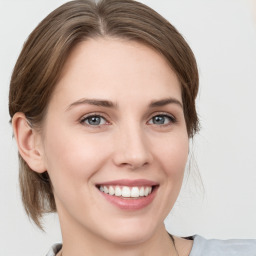 Joyful white young-adult female with medium  brown hair and grey eyes