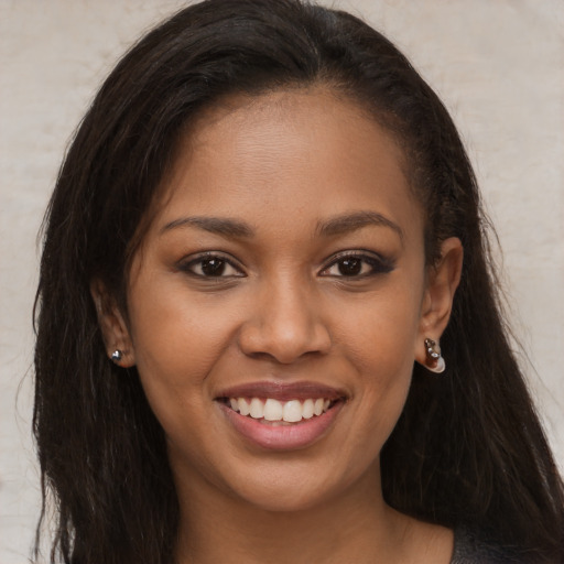 Joyful black young-adult female with long  brown hair and brown eyes