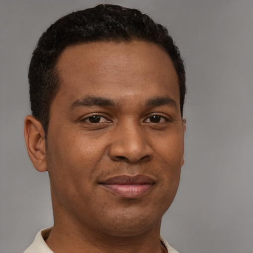 Joyful black young-adult male with short  brown hair and brown eyes