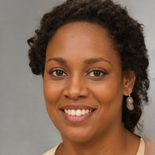 Joyful black young-adult female with long  brown hair and brown eyes