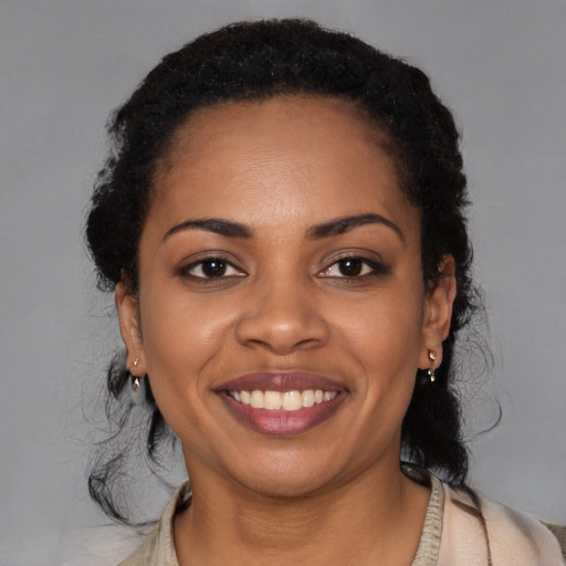 Joyful black young-adult female with long  black hair and brown eyes