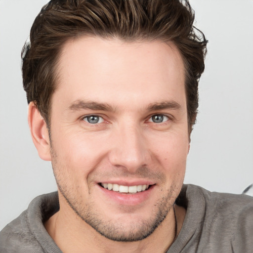 Joyful white young-adult male with short  brown hair and grey eyes