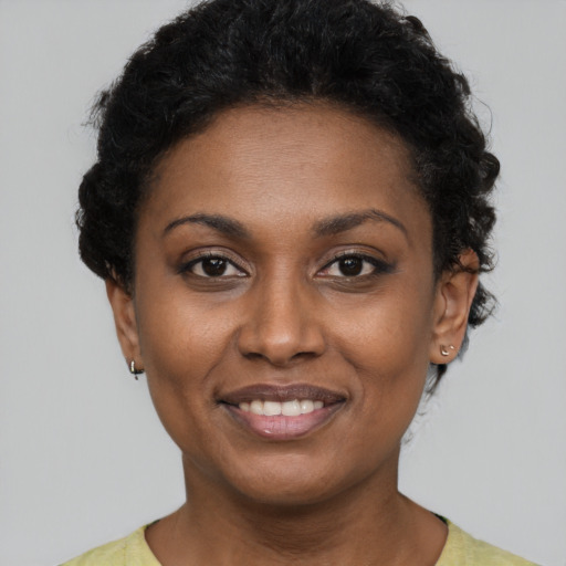 Joyful black young-adult female with short  black hair and brown eyes