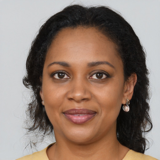 Joyful black young-adult female with long  brown hair and brown eyes