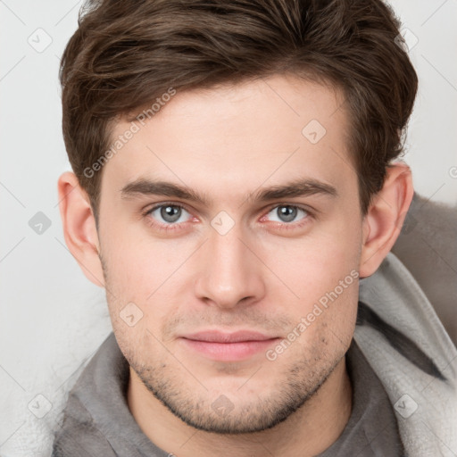 Joyful white young-adult male with short  brown hair and grey eyes