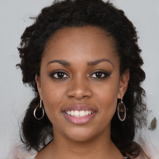 Joyful black young-adult female with long  brown hair and brown eyes