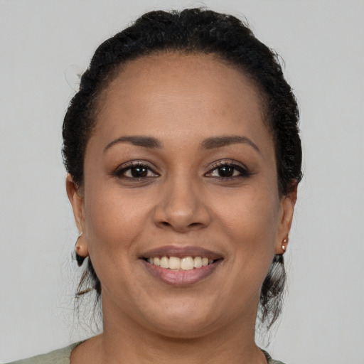 Joyful black young-adult female with long  brown hair and brown eyes