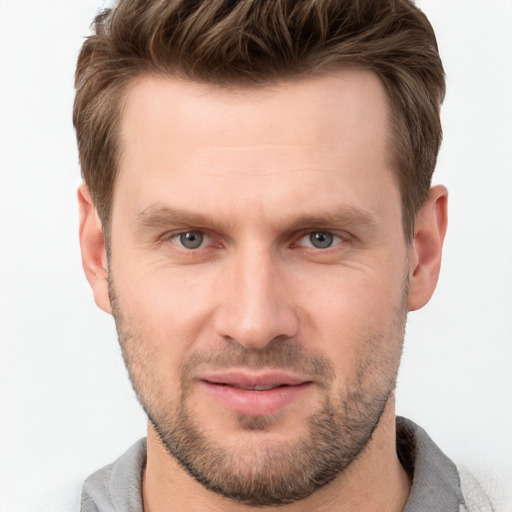 Joyful white young-adult male with short  brown hair and grey eyes