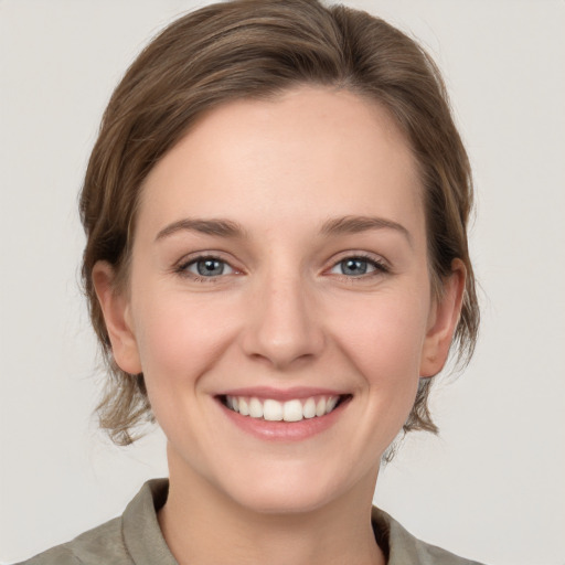 Joyful white young-adult female with medium  brown hair and grey eyes