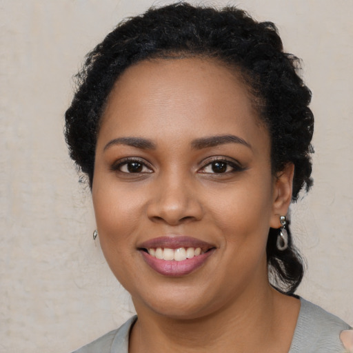 Joyful black young-adult female with long  brown hair and brown eyes