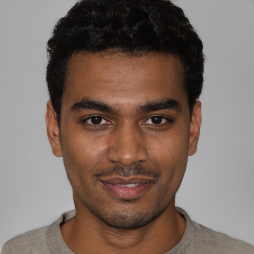 Joyful black young-adult male with short  black hair and brown eyes