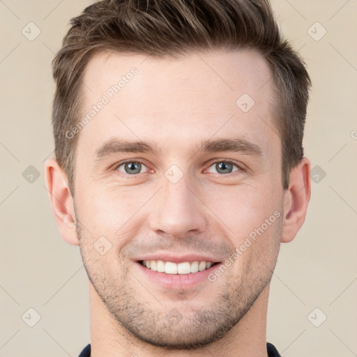 Joyful white young-adult male with short  brown hair and grey eyes