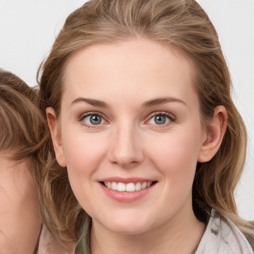 Joyful white young-adult female with long  brown hair and blue eyes