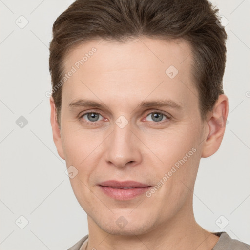 Joyful white young-adult male with short  brown hair and grey eyes