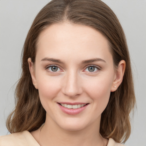 Joyful white young-adult female with medium  brown hair and grey eyes