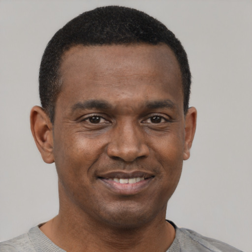 Joyful black young-adult male with short  black hair and brown eyes